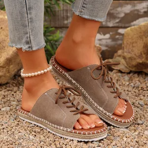 Détail de sandales en denim à lacets pour femmes avec une semelle tressée sur du gravier fin