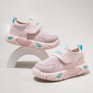 Ademende roze mesh kindersneakers met klittenband op een witte studio achtergrond