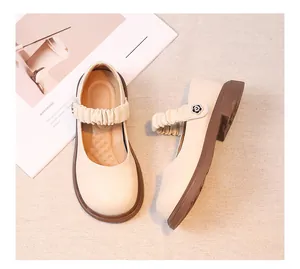Elegante cremefarbene Leder-Mary-Janes für Mädchen mit Rüschenriemen und dekorativer Blume.