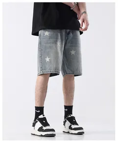 Close-up of men's light wash denim shorts with white star print and distressed detail