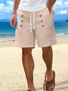 Detailed view of men's apricot cotton linen shorts with button accents on beach.
