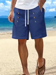 Close-up of blue cotton linen beach shorts with button details on a model