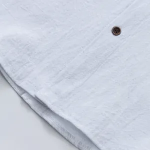 Macro della trama in lino bianco e del bottone marrone su una camicia casual da uomo.
