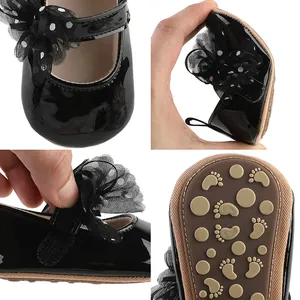 Gedetailleerde weergaven van zwart laklederen babyschoentjes met mesh strik en antislipzool.