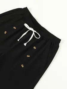 Close-up of black cotton linen shorts featuring white drawstring and button details