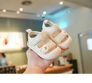 Close-up of off-white quilted baby sandals with M logo strap detail