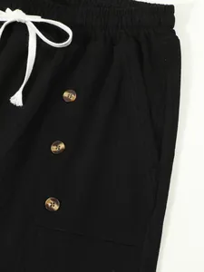 Close-up of black cotton linen shorts with white drawstring and decorative buttons