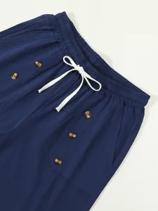 Close-up detail of navy cotton linen shorts with white drawstring and decorative buttons