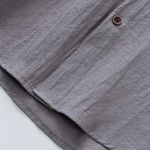 Primo piano della trama del tessuto di lino grigio e dettaglio bottone su camicia da uomo