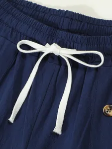 Close-up of the elastic waistband with a white drawstring on navy blue linen shorts