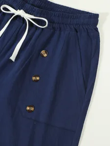 Detail view of navy cotton linen shorts with white drawstring and amber buttons