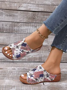 Detail view of women's peep-toe sandals with American flag print on a rustic background.