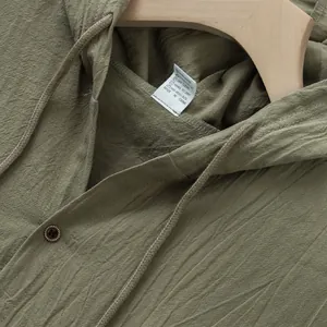 Primo piano di camicia con cappuccio in lino verde oliva con trama del tessuto e etichetta
