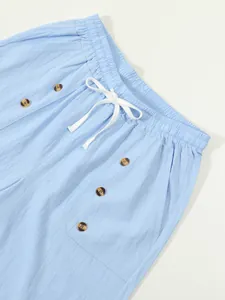 Close-up detail of blue cotton linen men's casual shorts with drawstring and brown buttons.