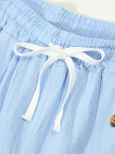 Detail of light blue cotton linen shorts with white drawstring and elastic waist