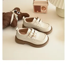 Girls beige British style leather shoes with double buckle straps on warm background