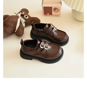 Detailed macro view of brown girls' British style loafers with double metal buckle straps