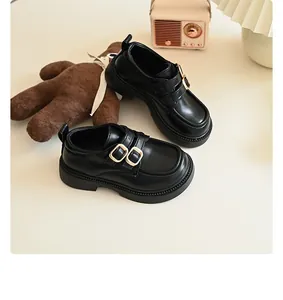 Close-up of black British style girls' leather loafers with stylish metal buckles