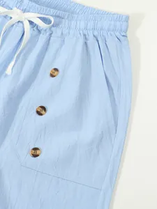 Detail of summer cotton linen shorts featuring elastic waist with white drawstring and buttons