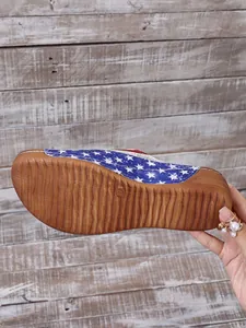Detailed macro view showing the textured brown sole and USA flag star pattern of a wedge sandal