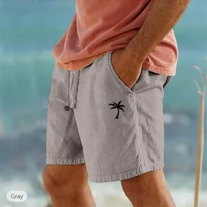 Dettaglio di pantaloncini da spiaggia grigi in cotone e lino con stampa a palma e coulisse.