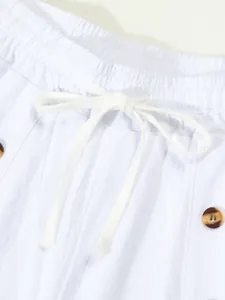 Detailed close-up of white cotton linen shorts waistband featuring drawstring and buttons