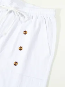 Detail of white cotton linen shorts with drawstring waist and decorative buttons