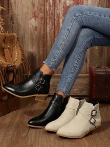 Detailed side view of pointed-toe ankle boots with buckle and zipper detail.