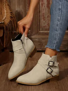 Side view of beige pointed toe block heel ankle boots with decorative buckles