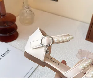 Macrodetail van crème prinsessensandalen voor meisjes met parelbandje en zilveren gesp