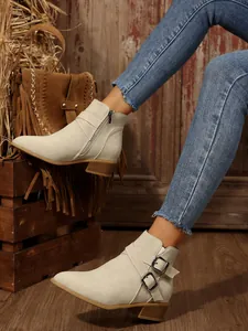 Stylish women's pointed-toe ankle boots with side buckles and block heels on model.