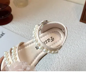 Detailopname van meisjessandalen met delicate parels en een zachte stoffen bloem.