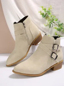 Detail view of beige pointed toe ankle boots with buckle straps and side zipper