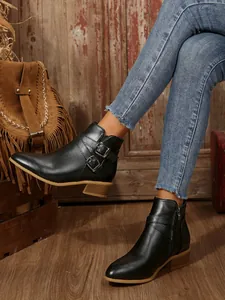 Close-up of black pointed-toe ankle boots with buckle straps and low block heel