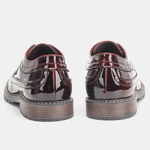 Primo piano di scarpe brogue in vernice bordeaux che mostrano il dettaglio del tallone.