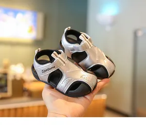 Nahaufnahme von silbernen und schwarzen Baby-Lauflernsandalen mit weichen Sohlen