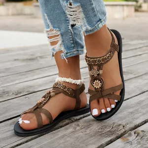 Detaillierte Ansicht brauner Boho-T-Riemen-Sandalen mit floralen Akzenten auf Holz