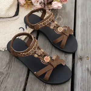 Nahaufnahme von flachen Ethno-Sandalen mit böhmischem Blumendekor auf Altholz