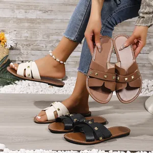 Close-up van stijlvolle platte sandalen met klinknagelaccenten en H-band ontwerp