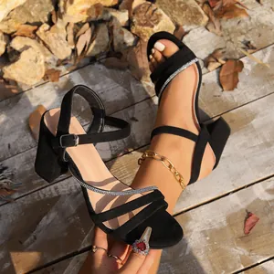 Detailansicht der eleganten schwarzen Wildledersandalen mit Blockabsatz und Strassriemen