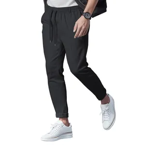 Close-up of men's slim-fit casual black trousers with drawstring waist and white sneakers