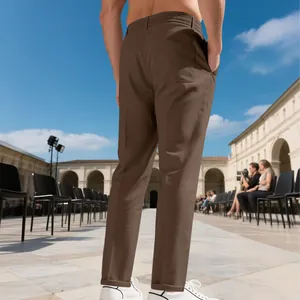Détail d'un pantalon décontracté marron coupe ajustée pour homme lors d'un défilé.