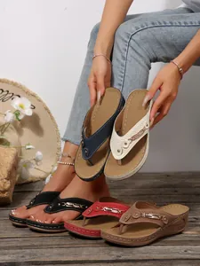 Close-up of assorted color wedge flip-flop sandals featuring elegant metal chain detail