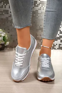 Κοντινό πλάνο από ασημί μεταλλικά sneakers με πλατφόρμα και λευκά κορδόνια στυλ