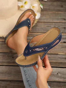 Detailed close-up of navy blue wedge thong sandals with metal chain and rhinestones