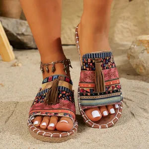 Primer plano de sandalias planas bohemias con borlas para mujer en una playa de arena