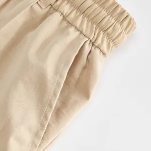 Close-up of khaki men's casual trousers showing elastic waistband and side pocket stitching
