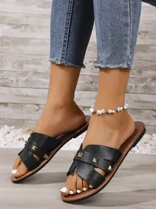 Detailopname van stijlvolle zwarte platte sandalen met gouden studs en slangenprint textuur