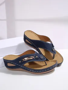 Detailed view of women's dark blue wedge flip-flops with golden metal chain decoration.