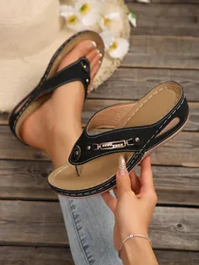 Close-up of stylish black platform flip-flops featuring a gold chain and rhinestone detail